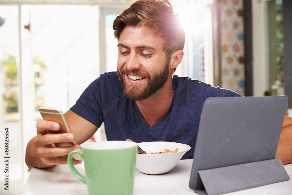 Man Eating Breakfast Whilst Using Digital Tablet And Phone Man Eating Breakfast Whilst Using Digital Tablet And Phone