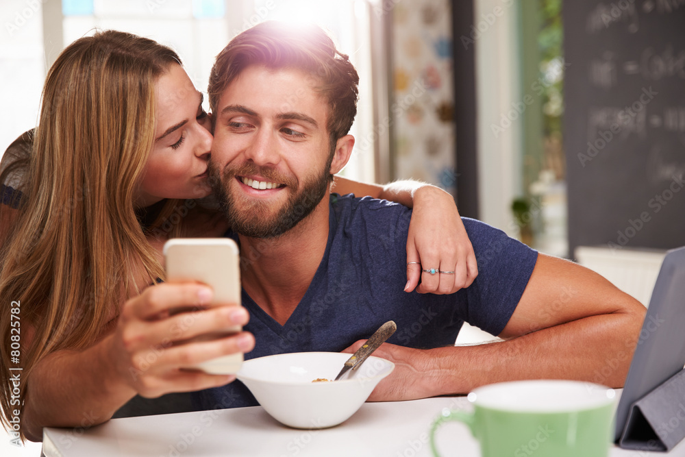 Couple Eating Breakfast Using Digital Tablet And Phone Couple Eating Breakfast Using Digital Tablet And Phone