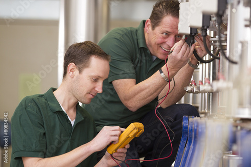Two male technician repairing agriculture machinery..