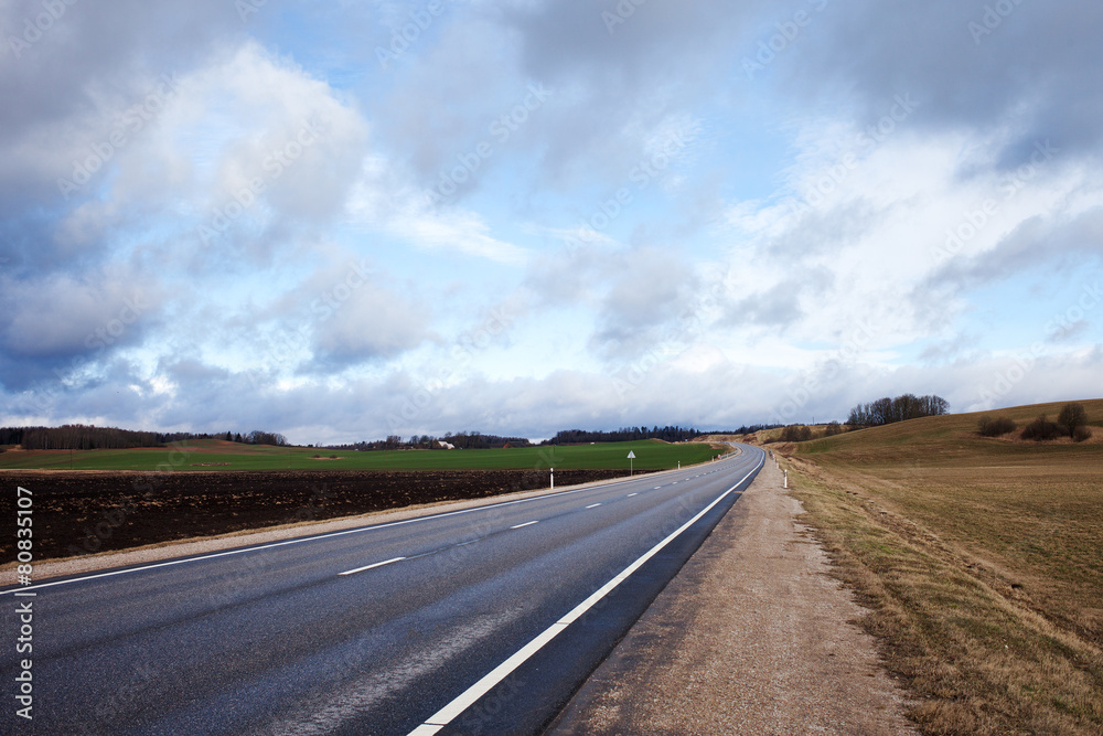 Cloudy landscape with asphalt road, Latvia, Europe.