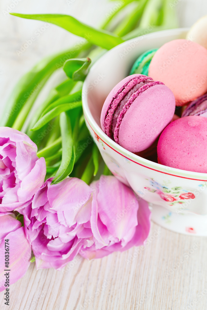 colorful macarons and tulips on wooden surface colorful macarons and tulips on wooden surface