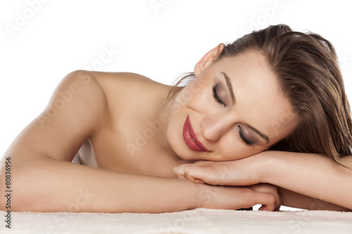 happy young woman lying on her hands on a white background