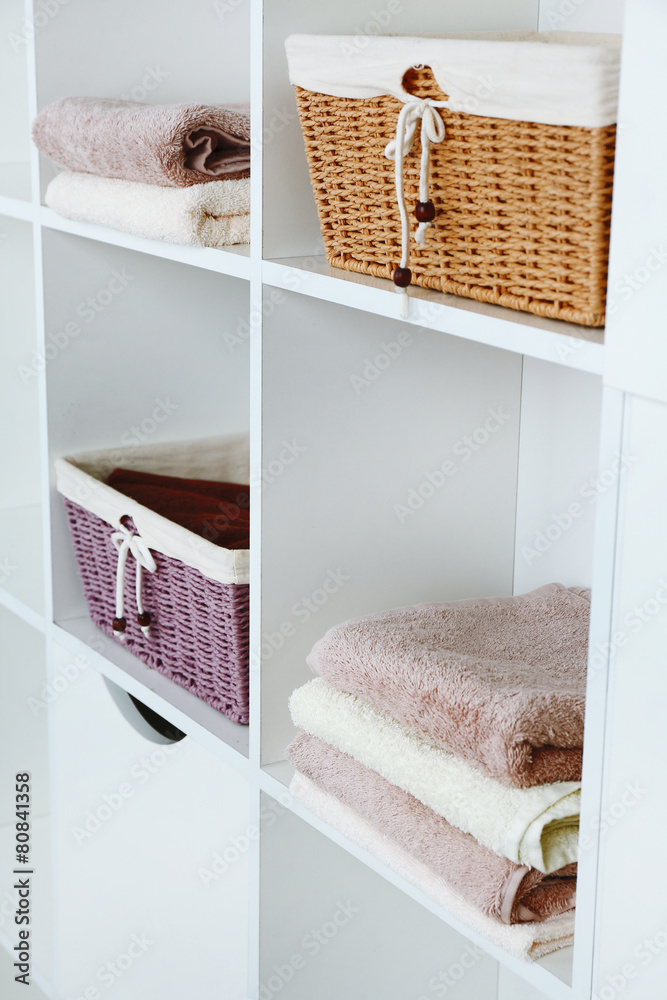 Pile of towels with wicker baskets on shelves of rack