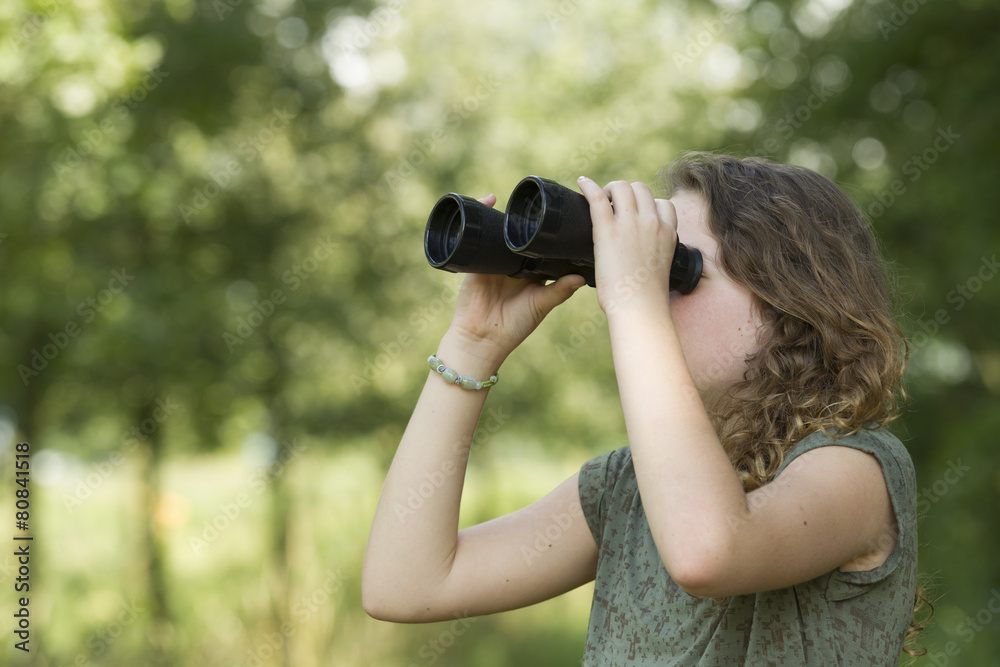 Pretty young girl exploring the environment with a binocular