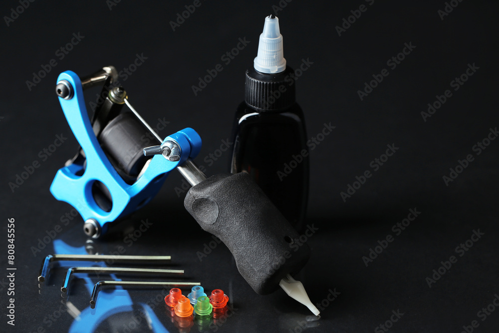 Naklejka premium Tattoo machine and tattoo Supplies, on dark background