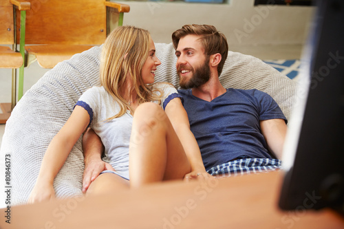 Young Couple In Pajamas Watching Television Together