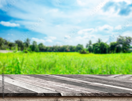 Empty Diagonal Wooden Table top at blurred green field and blue