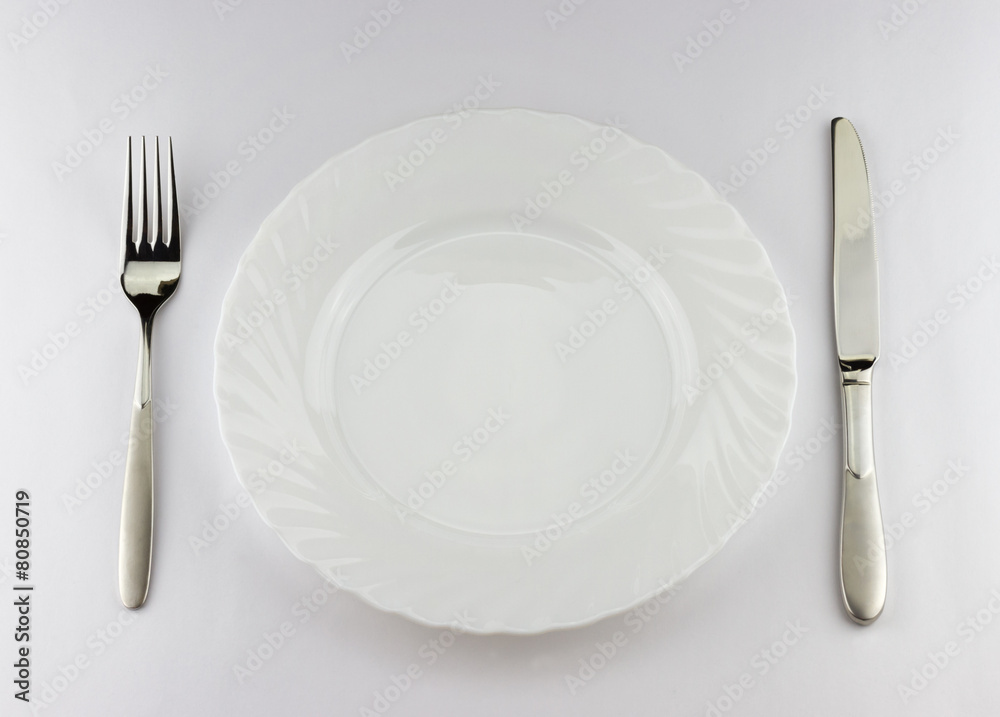 Top view of white plate with silver fork and knife 