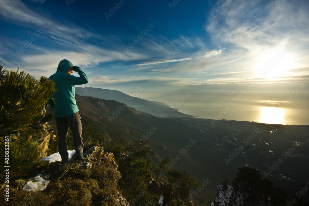 man standing on a cliff in mountains at sunrise man standing on a cliff in mountains at sunrise