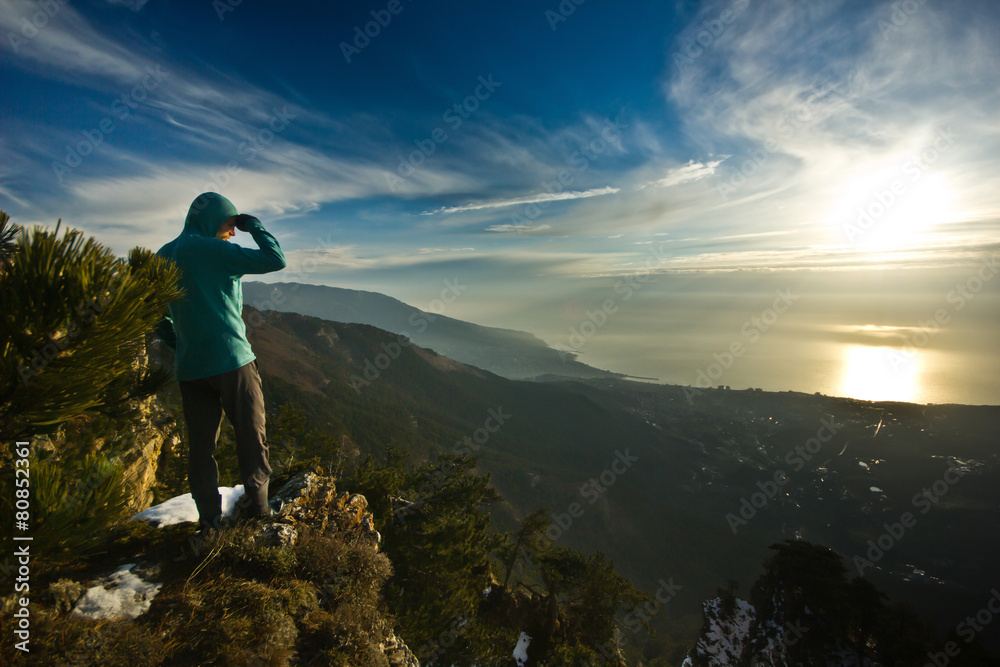 man standing on a cliff in mountains at sunrise