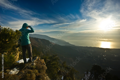 man standing on a cliff in mountains at sunrise