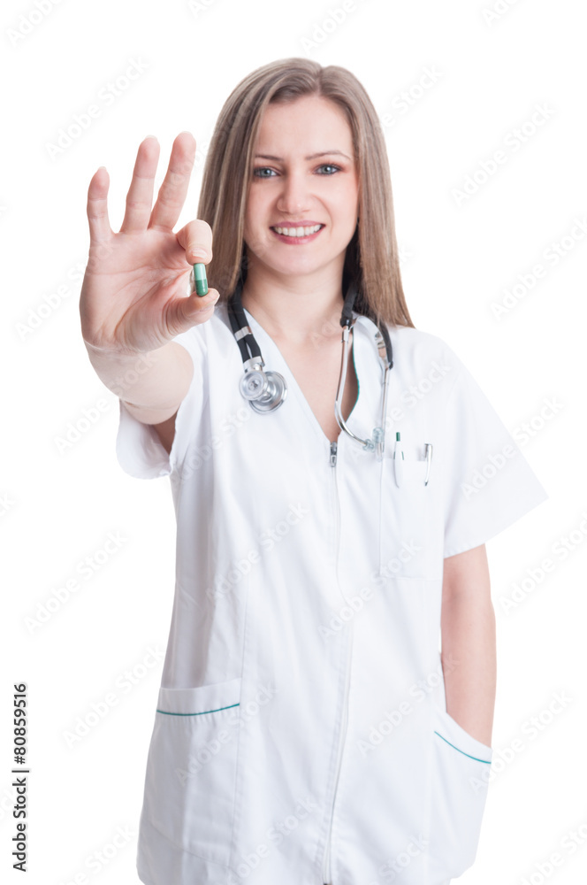 Young woman doctor showing a green natural pill Young woman doctor showing a green natural pill