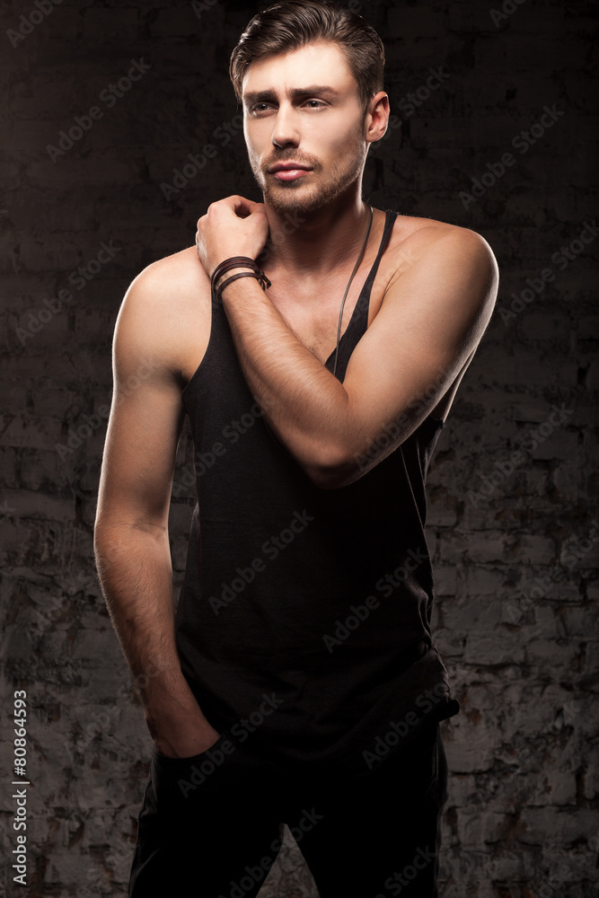 Obraz premium Stylish handsome man stands near a wall in black t-shirt