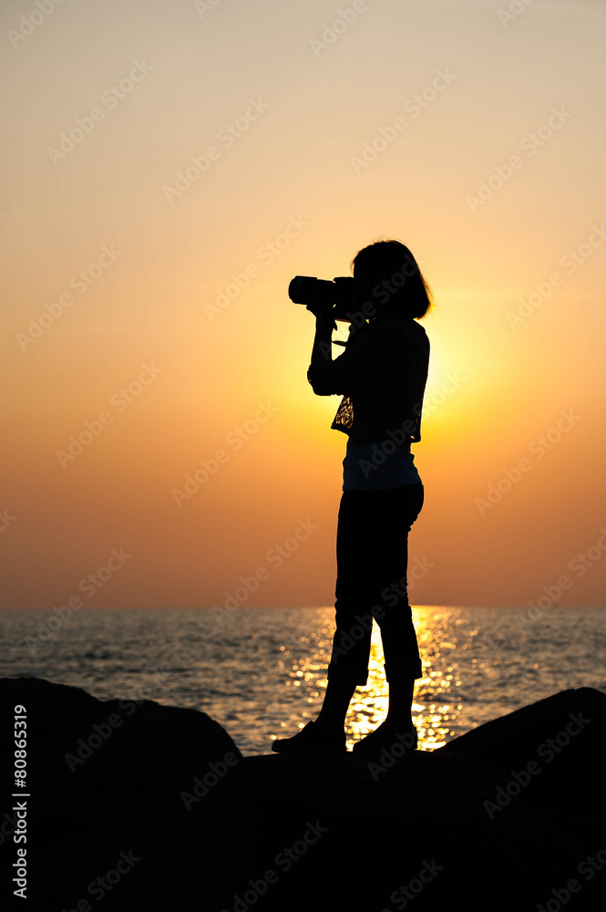 Silhouette woman photographer at sunset