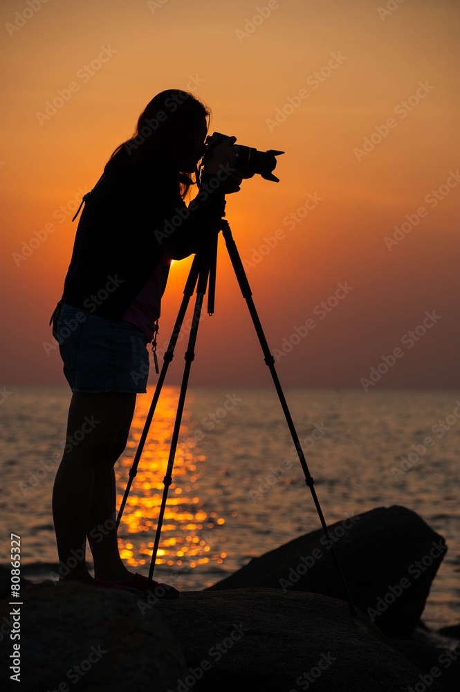 Silhouette woman photographer at sunset