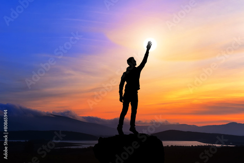 happy man with hand up on sunset background