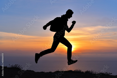 Running jumping man above sunset and mountain. Sport nature