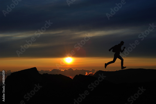 Running jumping man above sunset and mountain. Sport nature