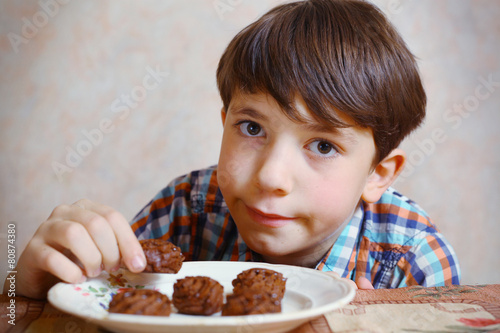 preteen handsome boy with chokolate sweets on the plate photo