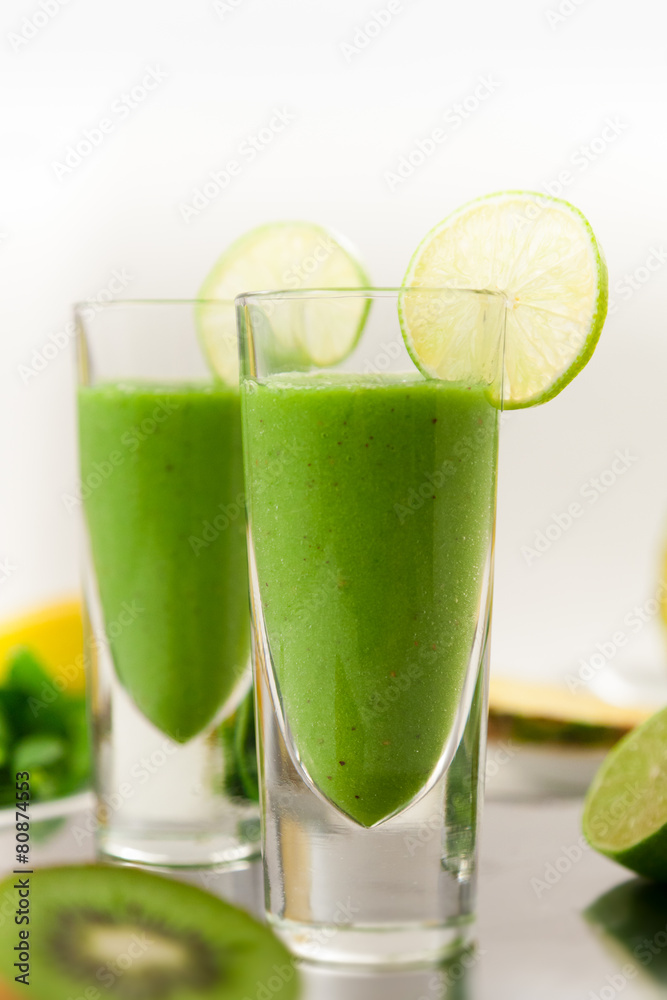 Green Smoothie with Lime and Fruits in Background Green Smoothie with Lime and Fruits in Background