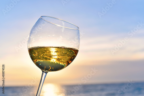 Romantic glass of wine sitting on the beach at colorful sunset
