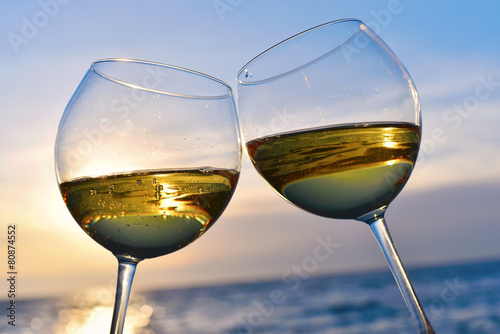 Romantic glass of wine sitting on the beach at colorful sunset