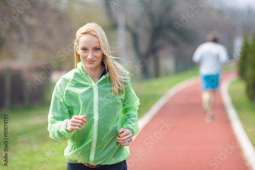 Portrait of beautiful blond girl jogging on running track