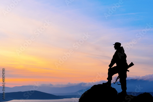Silhouette of military soldier officer with weapons at sunset