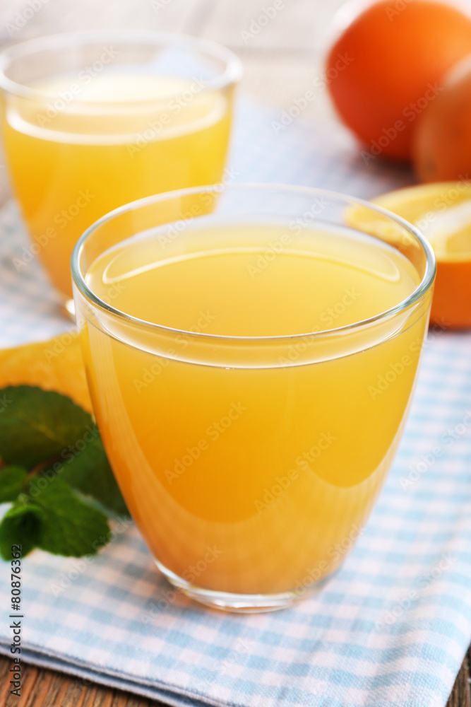 Fototapeta premium Glasses of orange juice with oranges on wooden table close up