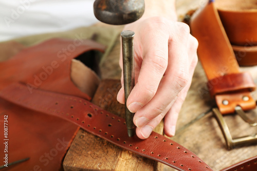 Repairing leather belt in workshop
