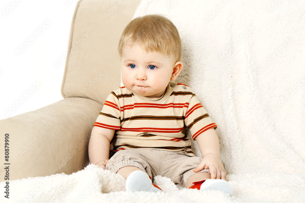 Cute baby boy on sofa, on light background Cute baby boy on sofa, on light background