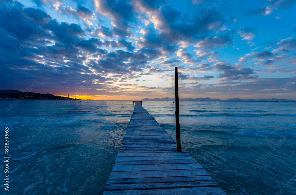 Wooden pier ar sunrise on Alcudia beach, Majorca island, Spain