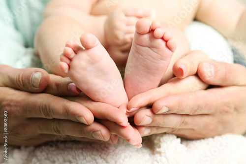 Newborn baby feet on father and mother hands, close-up © Africa Studio