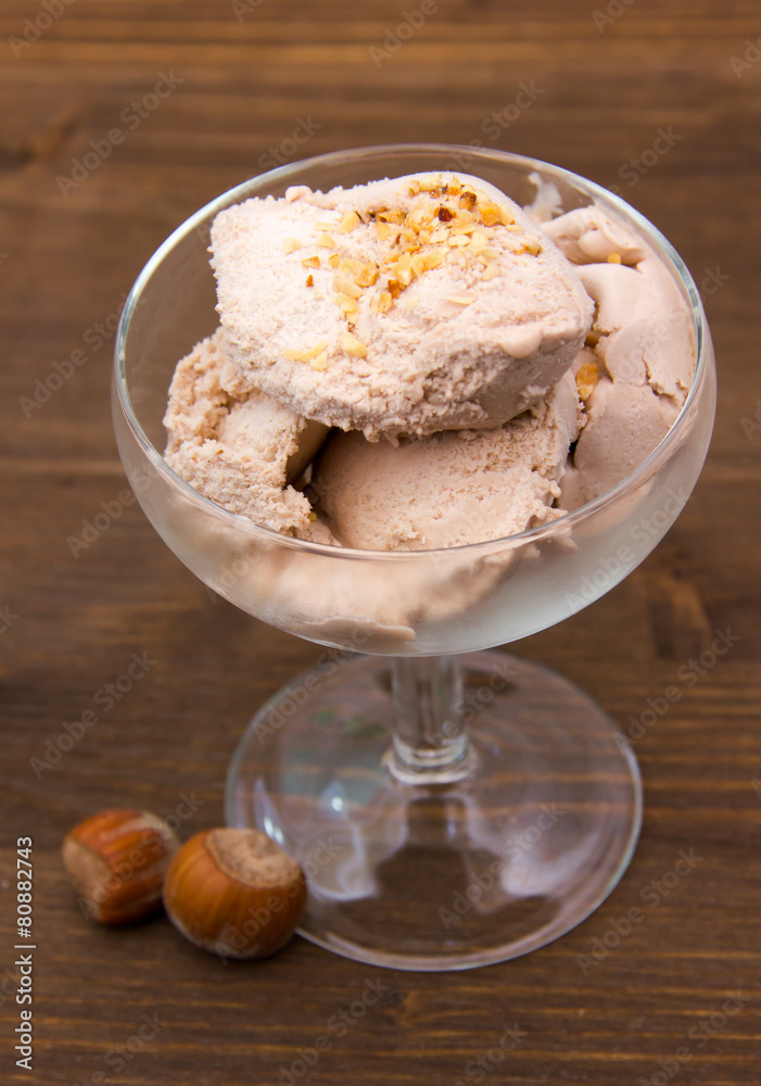 Cup of ice cream with hazelnut on wooden table top view Cup of ice cream with hazelnut on wooden table top view