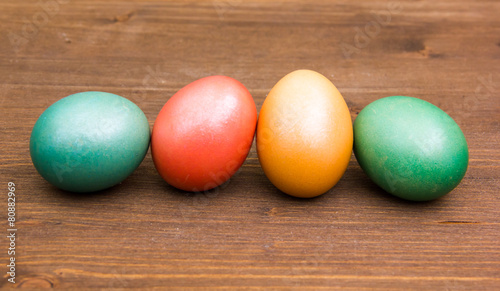 Row of colored eggs on wooden table