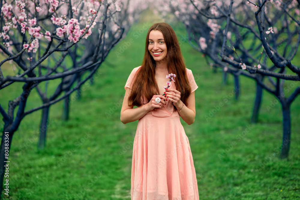 Woman enjoying spring in the green field with blooming trees Woman enjoying spring in the green field with blooming trees