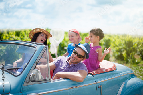 A lovely family is going on vacation in a convertible retro car © jackfrog