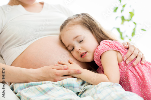 Cute child girl embracing pregnant mother