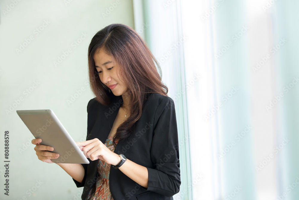 Young businesswoman standing while look at a tablet pc Young businesswoman standing while look at a tablet pc