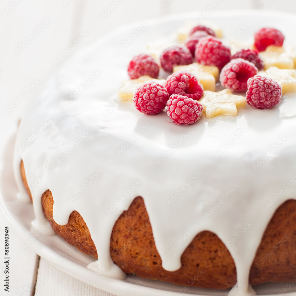 Fototapeta premium Banana Cake with Sugar Glaze Topped with Raspberries and Banana