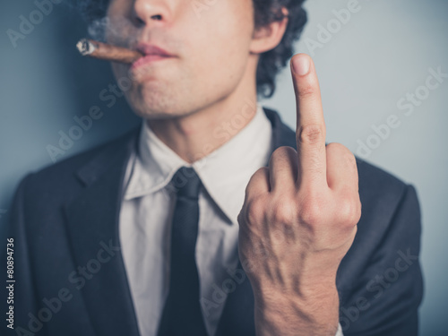 Young businessman with cigar showing rude gesture