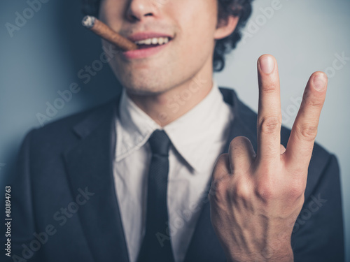 Young businessman with cigar showing rude gesture photo