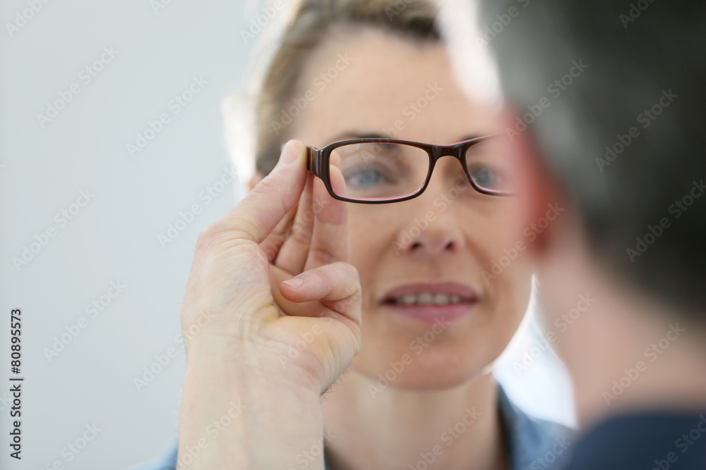 Mature blond woman with optician trying eyeglasses Mature blond woman with optician trying eyeglasses