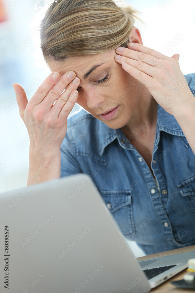 Woman in front of laptop suffering headache Woman in front of laptop suffering headache