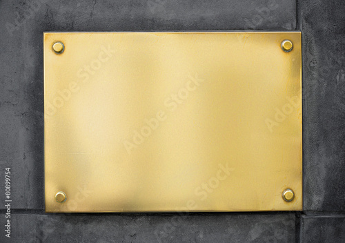 blank gold metal signboard or nameboard on concrete wall