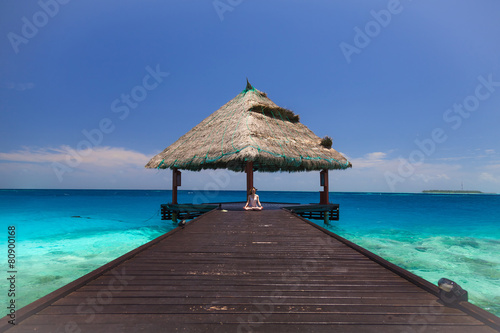 Beautiful girl meditating on the terrace in the Maldives