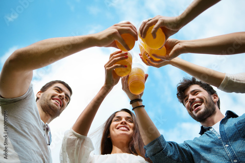 Vier Freunde mit Plastikbechern stoßen gemeisam an