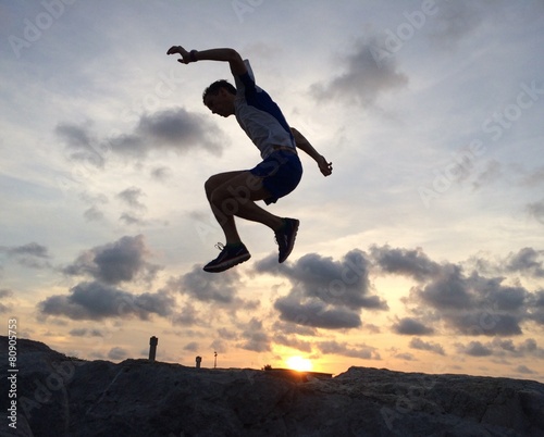 Male runner leaping at sunrise