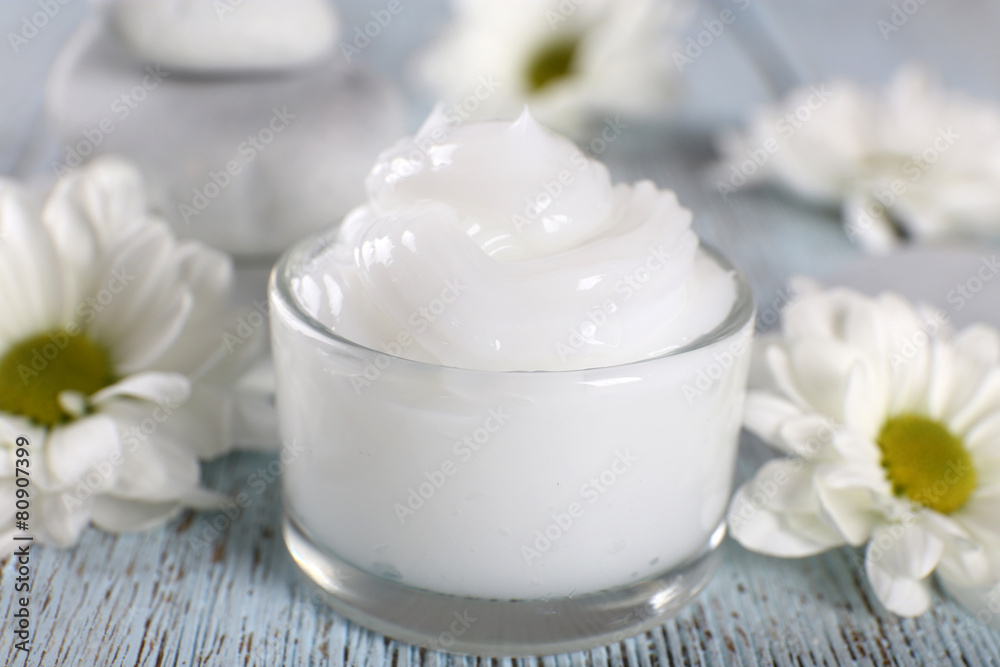 Cosmetic cream with flowers and spa stones on wooden background Cosmetic cream with flowers and spa stones on wooden background