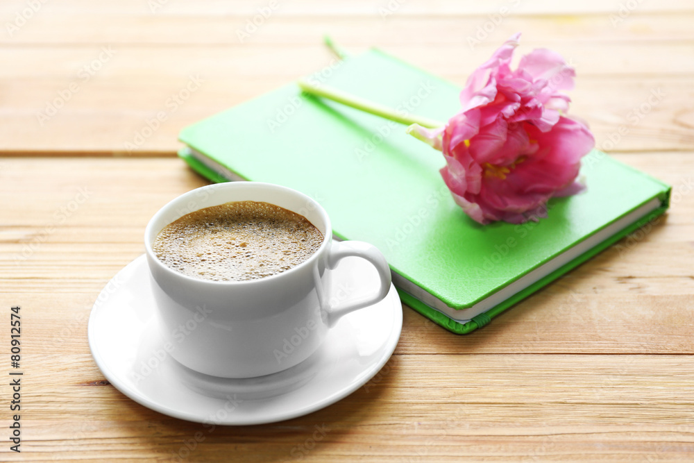 Cup of coffee with notebook and fresh flower Cup of coffee with notebook and fresh flower